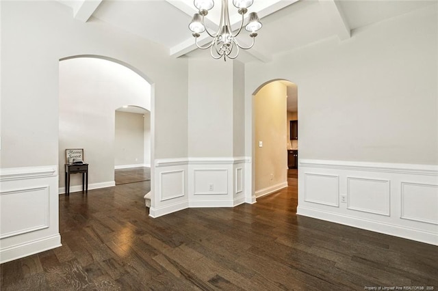unfurnished dining area featuring arched walkways, a chandelier, wainscoting, dark wood-type flooring, and beam ceiling