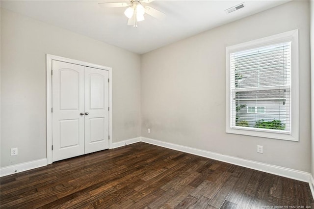 unfurnished bedroom featuring dark wood finished floors, baseboards, a closet, and ceiling fan