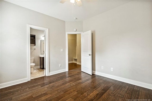 unfurnished bedroom featuring wood finished floors, ensuite bathroom, baseboards, and a ceiling fan