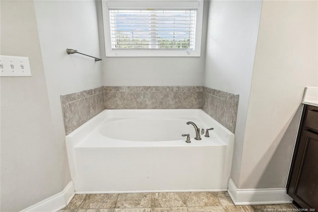 bathroom with a bath, vanity, and baseboards