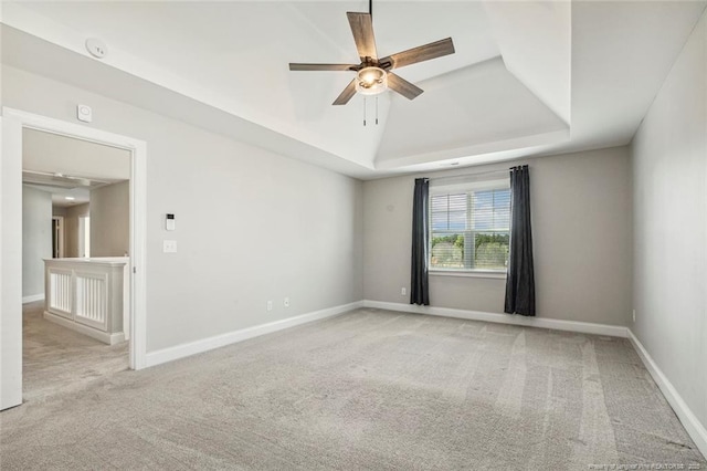 unfurnished room featuring ceiling fan, carpet flooring, a raised ceiling, and baseboards