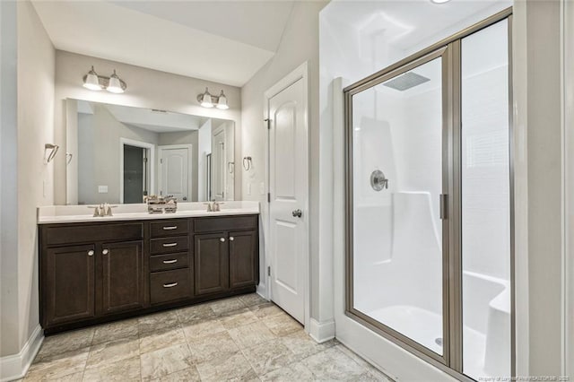 full bathroom featuring baseboards, a shower stall, and double vanity