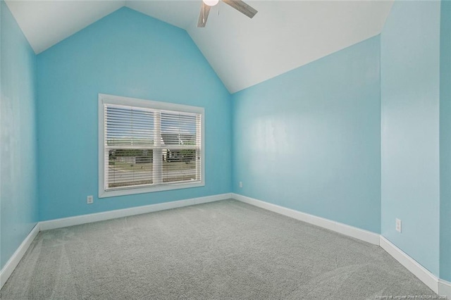 carpeted empty room with a ceiling fan, vaulted ceiling, and baseboards