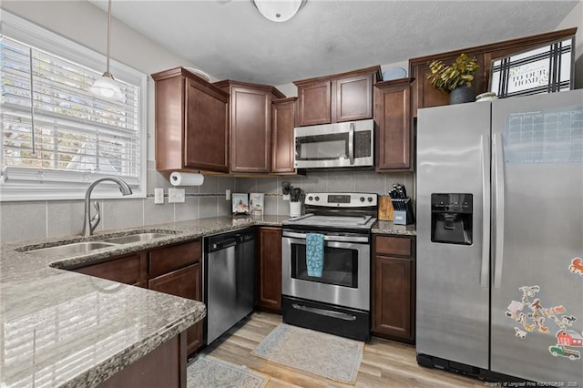 263 Autumn Ln, Raeford, NC 28376 - kitchen featuring appliances with stainless steel finishes, a sink, light wood finished floors, stone countertops, and backsplash