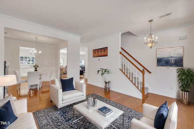 living room with stairway, wood finished floors, visible vents, and a notable chandelier