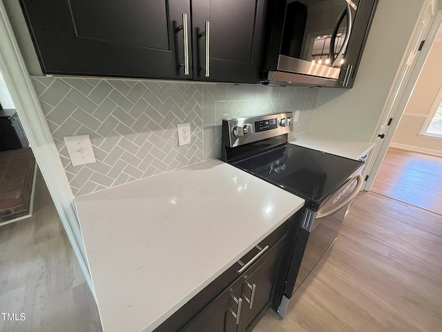 1116 Shadywood Ln, Raleigh, NC 27603 - kitchen featuring stainless steel appliances, dark cabinets, light wood-style flooring, tasteful backsplash, and light countertops