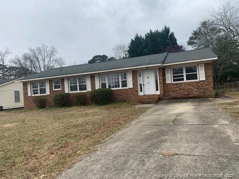 ranch-style home with brick siding, a front lawn, and driveway
