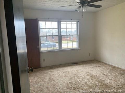 carpeted empty room featuring a textured ceiling and ceiling fan