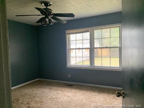 carpeted spare room featuring a textured ceiling, baseboards, and a ceiling fan