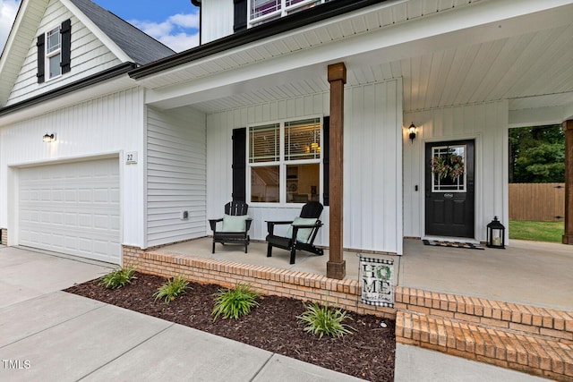 entrance to property featuring covered porch, driveway, and an attached garage