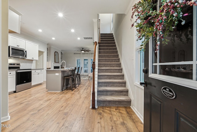 stairway with recessed lighting, wood finished floors, ceiling fan, crown molding, and baseboards