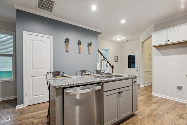 kitchen featuring stainless steel dishwasher, a sink, light wood-type flooring, light stone countertops, and ornamental molding
