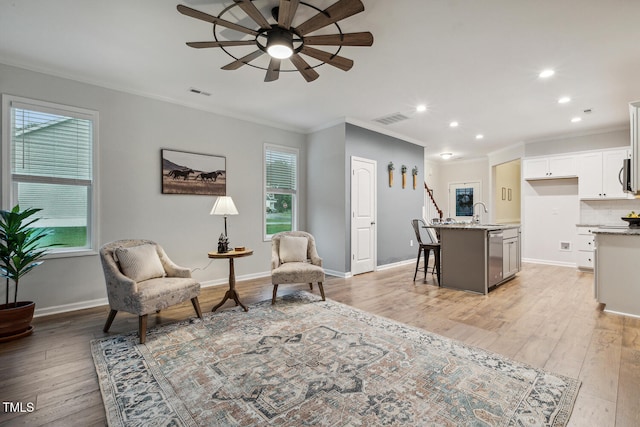 living room with ceiling fan, ornamental molding, recessed lighting, light wood-style flooring, and baseboards