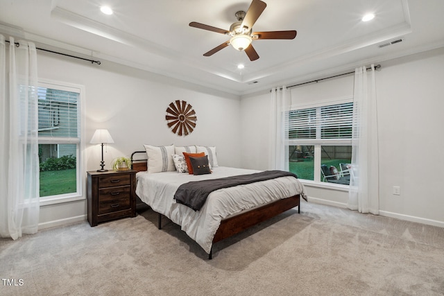 bedroom featuring a tray ceiling, recessed lighting, baseboards, light carpet, and crown molding