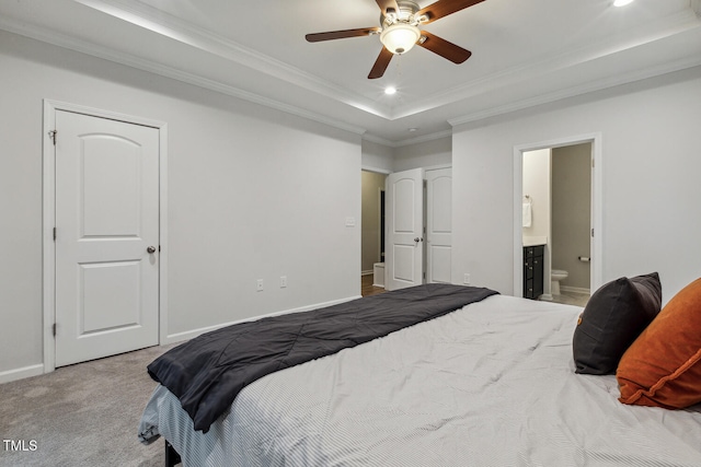 carpeted bedroom featuring a raised ceiling, crown molding, baseboards, recessed lighting, and connected bathroom