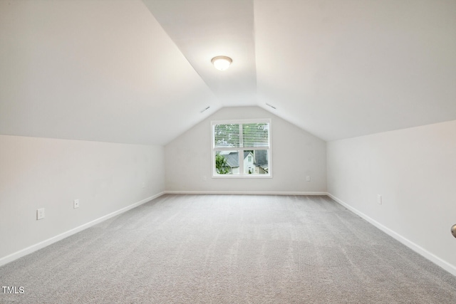 additional living space with lofted ceiling, light colored carpet, and baseboards