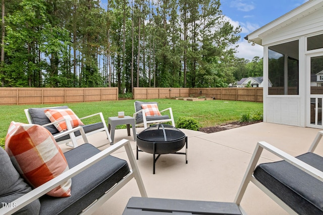 view of patio featuring an outdoor fire pit, a sunroom, and view of wooded area
