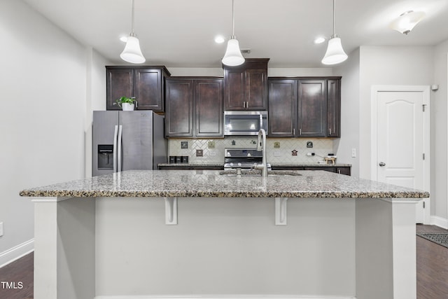 109 Belle Plain Dr, Morrisville, NC 27560 - kitchen featuring appliances with stainless steel finishes, a center island with sink, tasteful backsplash, light stone counters, and a breakfast bar area