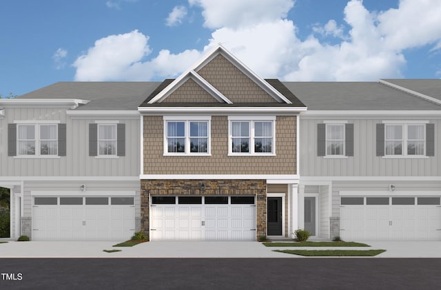 view of front of property with an attached garage, stone siding, driveway, and board and batten siding