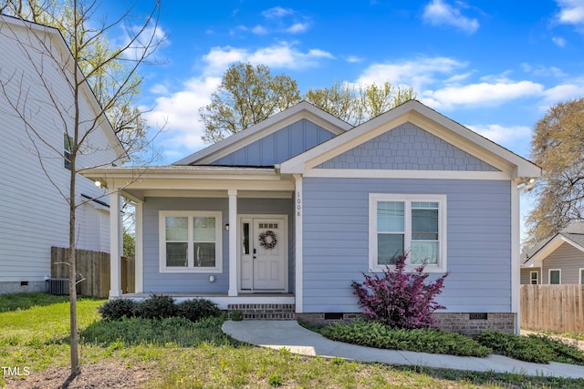 bungalow-style house featuring board and batten siding, a porch, fence, and crawl space