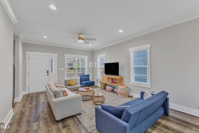living area with ornamental molding, ceiling fan, wood finished floors, and baseboards