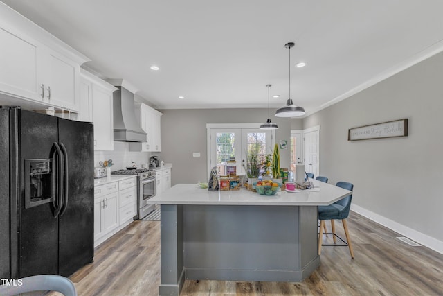 kitchen with white cabinets, black fridge with ice dispenser, a breakfast bar, premium range hood, and stainless steel range with gas cooktop