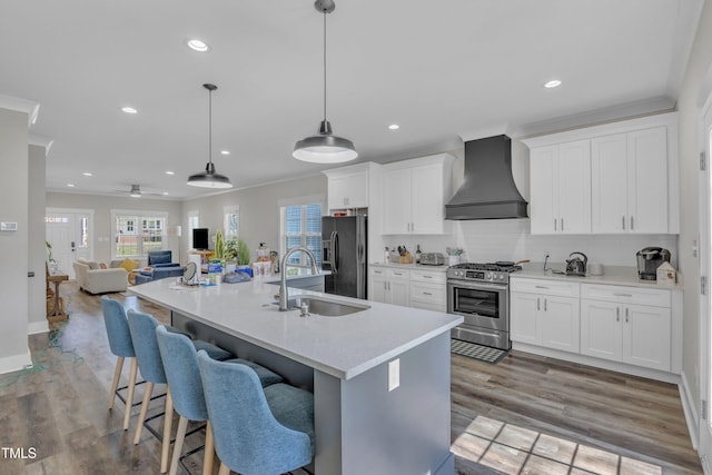 kitchen with ornamental molding, wall chimney range hood, gas range, black refrigerator with ice dispenser, and a sink