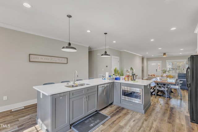 kitchen with ornamental molding, visible vents, gray cabinets, appliances with stainless steel finishes, and a sink