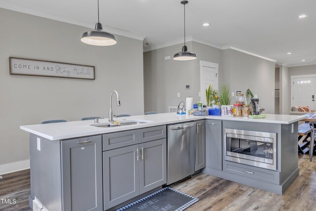 kitchen featuring gray cabinetry, appliances with stainless steel finishes, a sink, and ornamental molding