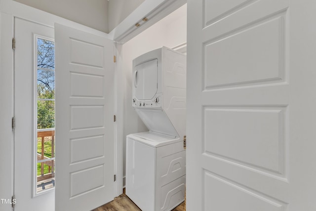 laundry area featuring stacked washing maching and dryer, plenty of natural light, laundry area, and light wood-style flooring