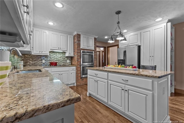 kitchen with a kitchen island, a sink, white cabinets, and stainless steel appliances