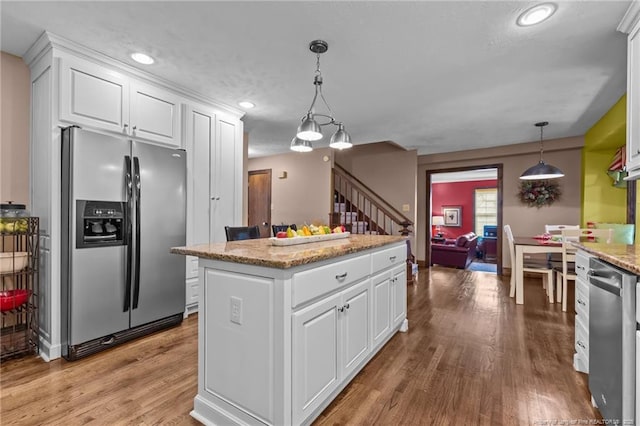 kitchen with light wood-style floors, a kitchen island, white cabinetry, and stainless steel appliances