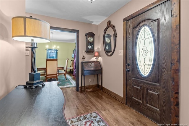 foyer with a chandelier, baseboards, and wood finished floors