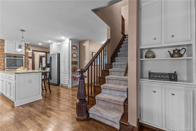 stairs with recessed lighting and wood finished floors