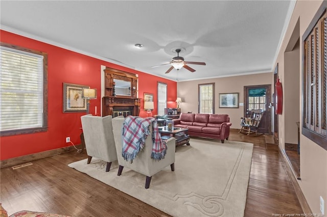 living area featuring crown molding, wood finished floors, baseboards, and a ceiling fan