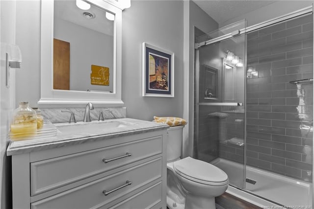 full bath with a shower stall, a textured ceiling, vanity, and toilet