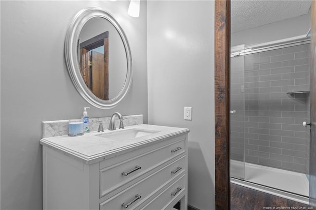 full bathroom with tiled shower, vanity, and a textured ceiling