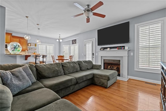 33 Woodbury Ln, Sanford, NC 27332 - living room with a fireplace with flush hearth, visible vents, light wood-type flooring, baseboards, and ceiling fan