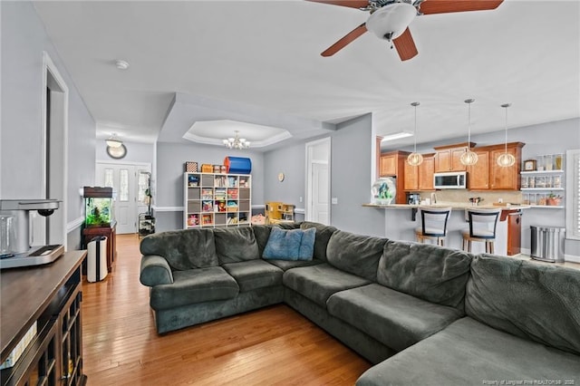 33 Woodbury Ln, Sanford, NC 27332 - living room featuring light wood-type flooring, a raised ceiling, and ceiling fan with notable chandelier