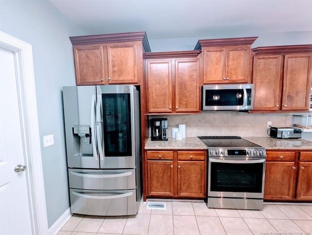 33 Woodbury Ln, Sanford, NC 27332 - kitchen with light stone counters, stainless steel appliances, backsplash, light tile patterned floors, and brown cabinetry