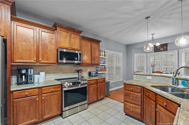 33 Woodbury Ln, Sanford, NC 27332 - kitchen featuring light tile patterned floors, a sink, a chandelier, brown cabinetry, and appliances with stainless steel finishes