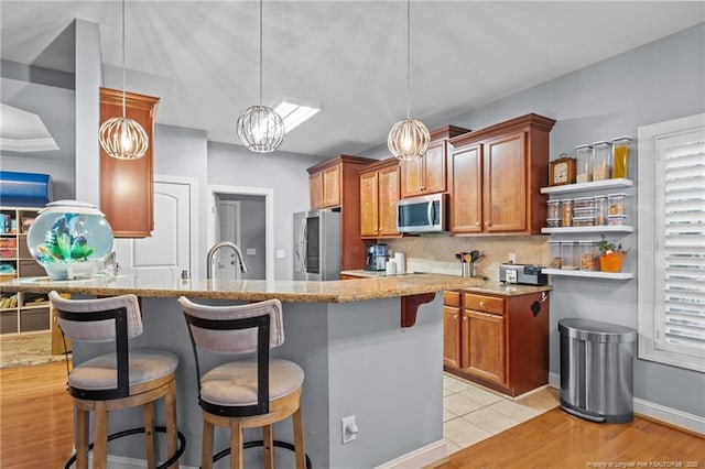 33 Woodbury Ln, Sanford, NC 27332 - kitchen with stainless steel appliances, a kitchen breakfast bar, backsplash, and brown cabinets