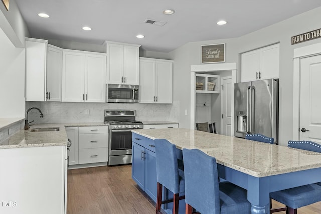 2801 Landon Ridge Dr, New Hill, NC 27562 - kitchen with a kitchen bar, a sink, light stone counters, dark wood-style floors, and stainless steel appliances