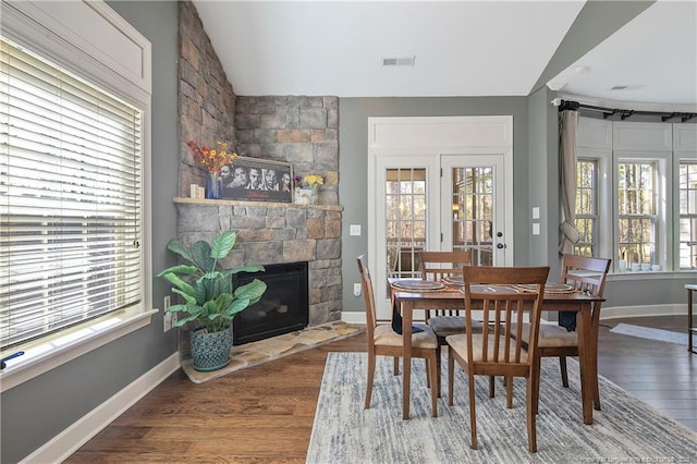 dining room featuring lofted ceiling, healthy amount of natural light, wood finished floors, and baseboards
