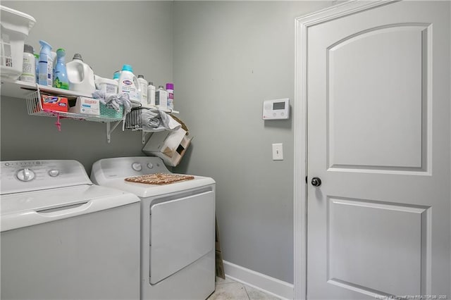 laundry room featuring washing machine and clothes dryer, light tile patterned floors, and baseboards