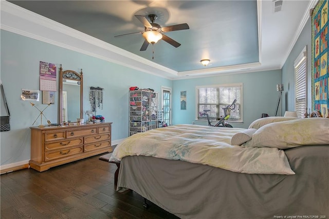 bedroom with a tray ceiling, dark wood-style flooring, baseboards, ornamental molding, and a ceiling fan