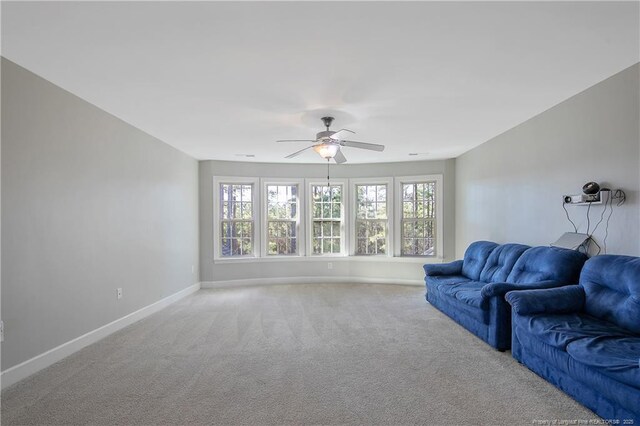 carpeted living area featuring plenty of natural light, a ceiling fan, and baseboards