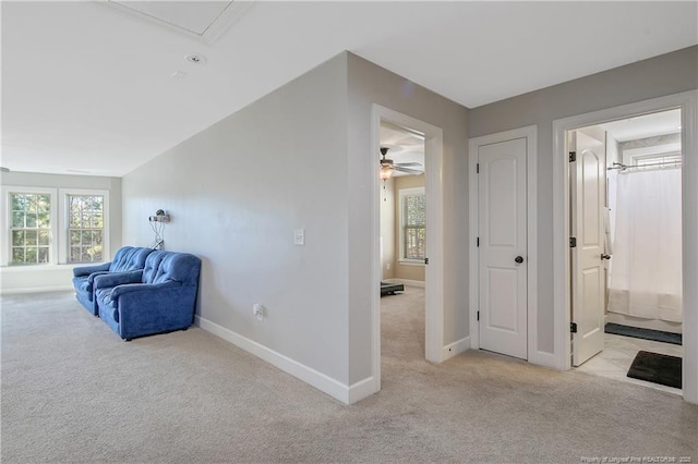 living area with light colored carpet, baseboards, and plenty of natural light
