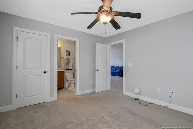 unfurnished bedroom featuring light colored carpet, baseboards, connected bathroom, and a ceiling fan