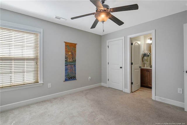 unfurnished bedroom featuring carpet flooring, baseboards, ensuite bath, and a ceiling fan